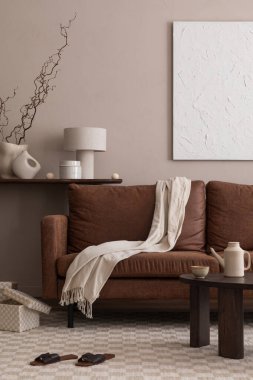 Sıcak ve rahat bir oturma odası. Poster çerçevesi, kahverengi kanepe bej ekose, ahşap sehpa, basit konsol, terlik, lamba ve kişisel aksesuarlar. Ev dekoru. Şablon.                                                                 