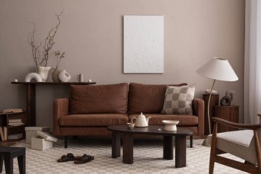 Poster çerçevesi, kahverengi kanepe, şık lamba, satranç baskısı halısı, kahve masası, küçük koltuklar ve kişisel aksesuarlarla dekore edilmiş rahat oturma odasının yaratıcı kompozisyonu. Ev dekoru. Şablon