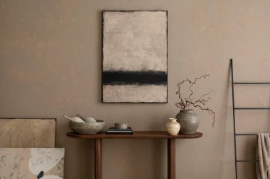 Ilık oturma odasının iç tasarımı poster çerçevesi, ahşap consola, siyah merdiven, gri kase, bej duvar, dallı vazo ve kişisel aksesuarlarla. Ev dekoru. Şablon.