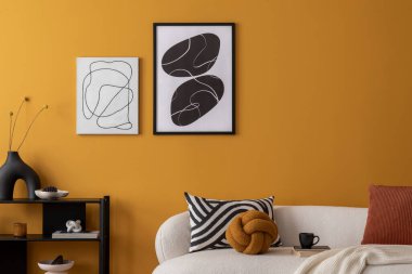 Poster çerçevesi, çiçek desenli kanepe, desenli yastıklar, siyah askı, ahşap sehpa, çiçekli vazo ve kişisel aksesuarları olan rahat oturma odasının iç tasarımı. Ev dekoru. Şablon.