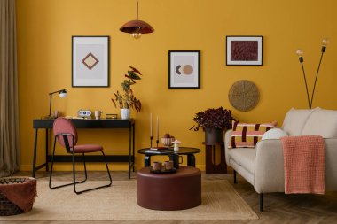 Sıcak ve rahat bir oturma odası. Poster çerçevesi, şık bir kanepe, siyah masa, burgund kahve masası, siyah lamba, desenli yastıklar, sepet ve kişisel aksesuarlar. Ev dekoru. Şablon.