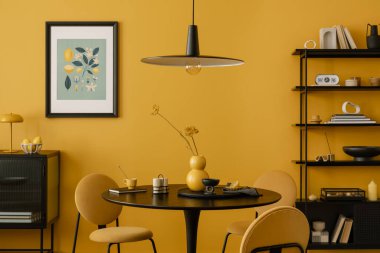 Sıcak ve rahat bir yemek odası. Poster çerçevesi, yuvarlak masa, sarı sandalye, siyah raf, şık lamba, kurutulmuş çiçekler ve kişisel aksesuarlarla süslenmiş vazo. Ev dekoru. Şablon.