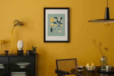 Yemek odasının sıcak ve rahat kompozisyonu poster çerçevesi, yuvarlak masa, sarı duvar, siyah büfe, kurumuş çiçekler ve kişisel aksesuarlarla süslenmiş cam vazo. Ev dekoru. Şablon.