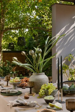 Masalı, kahverengi masa örtüsü, masa örtüsü, bardak, peçete, üzümlü kase, biber, çiçekli vazo, bahçe ve kişisel aksesuarlı estetik kompozisyon. Ev dekoru. Şablon.