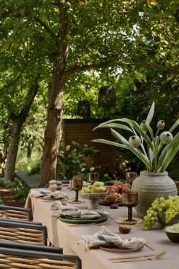 Masalı, kahverengi masa örtüsü, masa örtüsü, bardak, peçete, üzümlü kase, biber, çiçekli vazo, bahçe ve kişisel aksesuarlı estetik kompozisyon. Ev dekoru. Şablon.