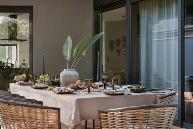 Terasın iç tasarımı masa, bahçe sandalyesi, çiçekli vazo, meyveli kase, sofra takımı, güzel bahçe ve kişisel aksesuarlar. Ev dekoru. Şablon. 