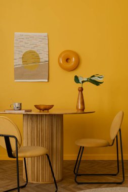 Yuvarlak masalı güneşli yemek odasının yaratıcı kompozisyonu, şık sandalye, yapraklı vazo, bitkiler, turuncu lamba, puf, cam kase, kilim halı, fincan ve kişisel aksesuarlar. Ev dekoru. Şablon.