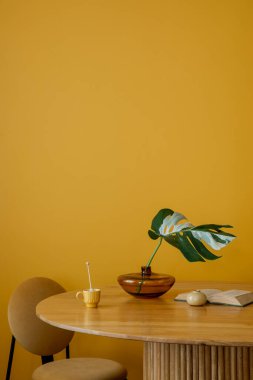 Yemek odasının iç kısımlarında desenli killim halı, yuvarlak masa, kitaplar, fincanlar, saksıdaki bitkiler, turuncu lamba ve kişisel aksesuarlar var. Ev dekoru. Şablon.