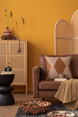 İçi sıcacık oturma odasının ahşap, kahverengi kanepe örgülü sepet, siyah sepet, örülmüş sepet, bölünmüş duvar ve kişisel aksesuarlarla estetik bileşimi. Ev dekoru. Şablon.