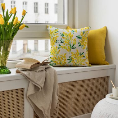 Tarafsız renk paleti olan Paskalya temalı bir oturma odası. Seramik tavşan heykelcikleri, pastel yumurtalar ve beyaz bir vazoda taze sarı lalelerle süslenmiş yuvarlak bir sedir, şenlikli bir dokunuş ekler..