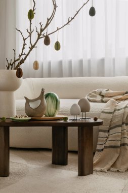 Seramik tavşanlar, dekoratif yumurtalar ve desenli fırlatışlarla süslenmiş bir sehpası olan şık bir Paskalya ortamı. İskandinav minimalizminin ve mevsimsel cazibenin mükemmel bir karışımı.