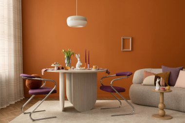 Ahşap bir yemek masası, şık mor sandalyeler ve yumuşak mevsimlik dekorasyonlar içeren çağdaş Paskalya temalı iç mekan..