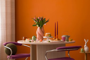 Canlı laleler, mumlar ve Paskalya ziyafetleriyle süslenmiş ahşap bir masa ile süslü şık bir yemek düzeni..