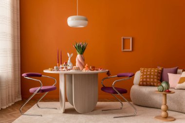 Ahşap bir masa, rahat bir dekor ve dikkatlice tasarlanmış mevsimlik dekorasyonlu estetik Paskalya temalı yaşam alanı..