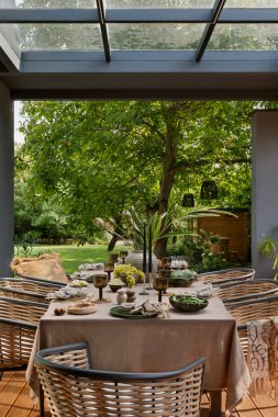 Terasın iç tasarımı masa, bahçe sandalyesi, çiçekli vazo, meyveli kase, sofra takımı, güzel bahçe ve kişisel aksesuarlar. Ev dekoru. Şablon. 