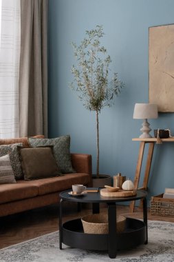 Ilık oturma odasının iç tasarımı poster çerçevesi, masa, sandalye, kanepe, bej büfe, şık lamba, mavi duvar ve kişisel aksesuarlar. Ev dekoru. Şablon.