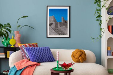 Modern and colorful interior of living room with design boucle sofa, mock up poster, shelf, plants, decorations and personal stuff. Home decor.	