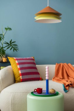Modern oturma odasının iç dekorasyonu renkli dekorasyonlar ve aksesuarlar, bitkiler, kanepe, sehpa, lamba ve bitki. Mavi duvar. Ev dekoru. Şablon