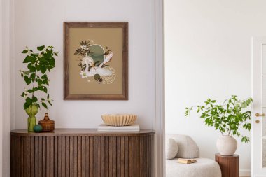 Ahşap bir dolabın içinde saksı bitkileri, dekoratif nesneler ve kitaplarla süslenmiş. Güneş patlaması tasarımı içeren canlı bir sanat eseri renk katıyor. Konforlu oturma alanı arka planda görünüyor.