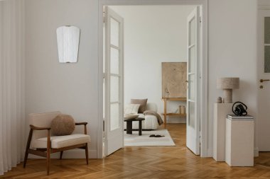 Yüzyıl ortası modern koltuğu, hafif ışıklandırması ve nötr tonu olan rahat, minimalist bir yaşam alanı. Odada cam kapılar, desenli duvarlar ve zarif bir dekor var. Huzurlu ve davetkar bir atmosfer yaratıyor..