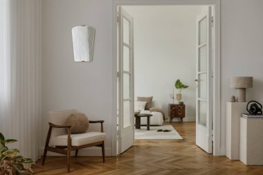 Yüzyıl ortası modern koltuğu, hafif ışıklandırması ve nötr tonu olan rahat, minimalist bir yaşam alanı. Odada cam kapılar, desenli duvarlar ve zarif bir dekor var. Huzurlu ve davetkar bir atmosfer yaratıyor..