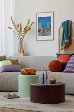 Renkli yastıklarla süslenmiş, modern sanat ve canlı dekor aksanlarıyla tamamlanmış bej renkli bir kanepesi olan rahat bir oturma odası.. 