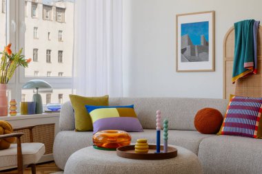 Zarif ve davetkar bir oturma odası, nötr renkli bir kanepe, canlı turuncu çiçekler, ve modern ve eğlenceli dekorların bir karışımı. Ev dekorasyonu ve poster çerçevesi.