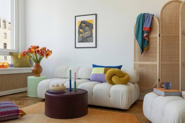 Yumuşak mobilyaları, renkli yastıkları ve modern vazolarda taze çiçekleri olan parlak ve neşeli bir oturma odası. Tarz ev dekoru.