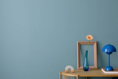 Mavi lambalı minimalist tasarım, cam vazoda tek bir çiçek, ve basit geometrik dekor, sakin, modern bir atmosfer yaratıyor..