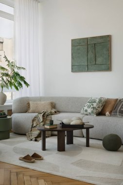 Modern bir iç mekan, rahat bir kanepe ve dikkatlice seçilmiş detaylar. Yeşil aksanlar ve tahta elementler doğal ve sakinleştirici bir karakter ekler..