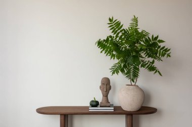 Heykel büstü, yeşil vazo ve yeşillik içeren minimalist konsol tarafsız bir ortamda doğal zarafeti somutlaştırıyor. Ev dekoru.