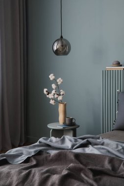 Yatak odası düzenlemesi, yumuşak mavi yatak başlığı, katmanlı çarşaflar ve hoş dekorasyon unsurları..