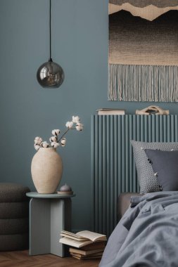 Koyu mavi bir paleti, dokulu yastıkları ve dokuma duvar halısı olan rahat bir yatak odası. Yumuşak tekstil ve sıcak ışıklandırma dingin ve modern bir geri çekilme yaratır..