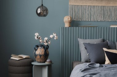  Seren yatak odası, yan masada vazo, yumuşak mavi yatak örtüsü, ve dokusu ve sıcaklığı olan dokuma halısı..