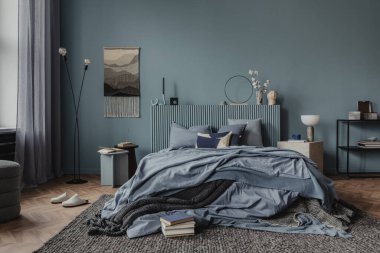 Samimi bir yatak odası alanı, desenli atışlar, nötr renkli yastıklar ve sıcak aydınlatmalarla süslenmiş. Ev dekoru. Mavi tonlar.