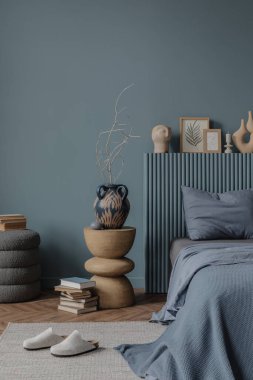 Pamuk saplı desenli bir yatak başlığı seramik bir kafa heykeli ve istiflenmiş kitaplar modern ve doğal tasarım dengesini yakalıyor..