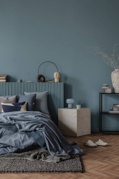 Гармоничное расположение мягких постельных принадлежностей в оттенках синего, в сочетании с декоративными подушками и тонким освещением, чтобы вызвать спокойное настроение.