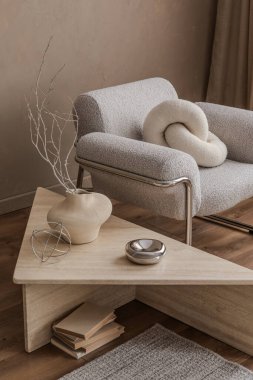 Koltuk, minimalist bir vazo ve kurumuş çiçekler içeren şık bir oturma odası kompozisyonu, ince dokuları ve doğal maddeleri vurguluyor.. 