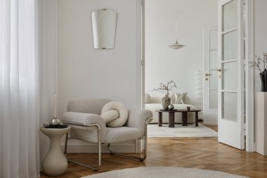 Şık bir oturma odası. İçinde küçük bir koltuk, soyut sanat eserleri ve yumuşak mobilyalar var. Sakin ve davetkar bir modern alan..