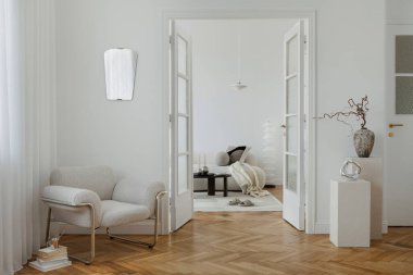 Açık yaşam alanı olan sofistike bir iç mekan, bir boucle koltuk, nötr tekstil ve heykel dekoru içeriyor. Beyaz duvarlar ve ahşap döşemeler sıcaklık katıyor.