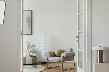  Pürüzsüz, modern bir salon, küçük bir koltuk, bir heykel lambası ve zarif dekoratif aksanları olan, rafine edilmiş, nötr renkli bir alanı vurgulayan..