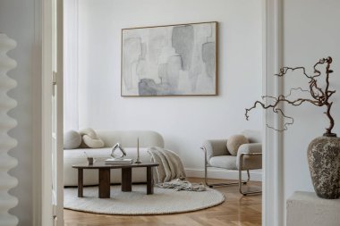 Bukle kanepeli şık bir oturma odası, soyut sanat eserleri, ve nötr renk paletinde heykel mobilyaları..