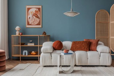 Basit bir koltuğu olan bej desenli bir duvar vazo ve kitaplarla süslenmiş, minimalist bir sanat eseriyle tamamlanmış üç köşeli ahşap bir masa..