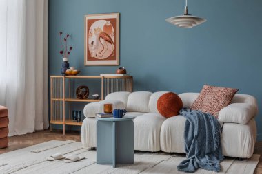 Koyu mavi bir duvara dayalı rahat bir kanepe. Modern, davetkar bir yaşam alanı için yanmış turuncu ve kehribar aksanlı..