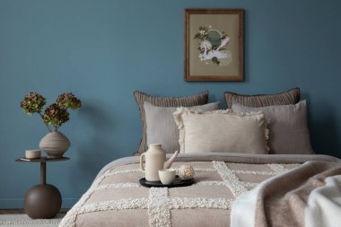 Şık yatak odasının iç dekorasyonu poster çerçevesi, yatak, gri yatak odası, mavi duvar, şık komodin, çiçekli vazo ve kişisel aksesuarlarla süslenmiş. Ev dekoru. Şablon. 