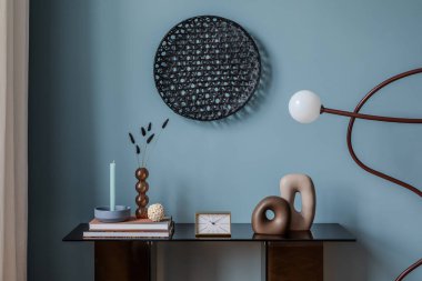 Derin mavi aksanlı bir duvarı, füme cam konsol masası ve çağdaş ve Japandi etkilerini birleştiren heykel dekoru olan modern bir iç mekan..