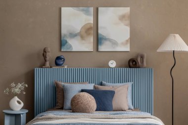 Mavi tonlu yatak odasına daha geniş bir perspektif, heykel parçaları, bir zemin lambası, ve dingin atmosferi arttıran yumuşak ışıklandırma.