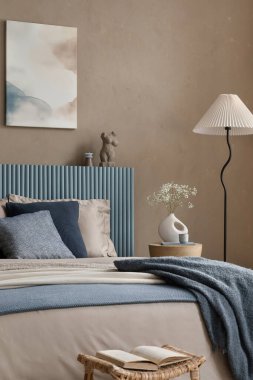 Rahat, doğadan esinlenilmiş, toprak renkleri, doğal dokuları ve bej ve yumuşak mavilerden oluşan rahatlatıcı bir paleti olan bir yatak odası..
