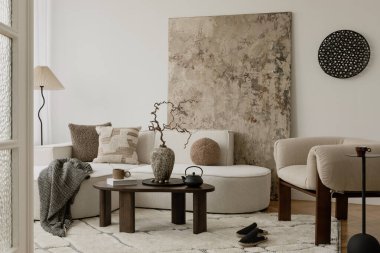 Parlak nötr yaşam alanı, dokulu yastıklar, yumuşak bukle koltuklar, ve odak noktası olarak seramik vazo..