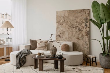 Yuvarlak kanepe, kırsal dokular ve heykel ve organik tasarım elementlerinin karışımıyla aydınlık bir oda..